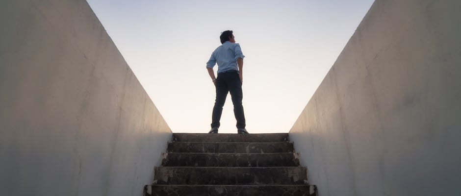 image of man at the top of stairs looking upward