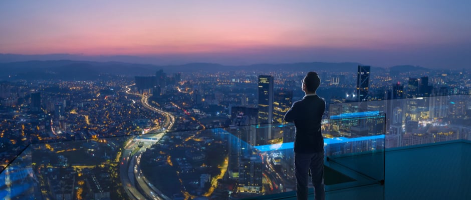 image of businessman looking out a window at cityscape at sunset