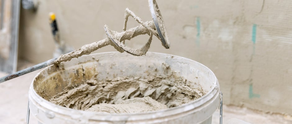 image of tool used to mix cement for stucco with bucket of wet cement