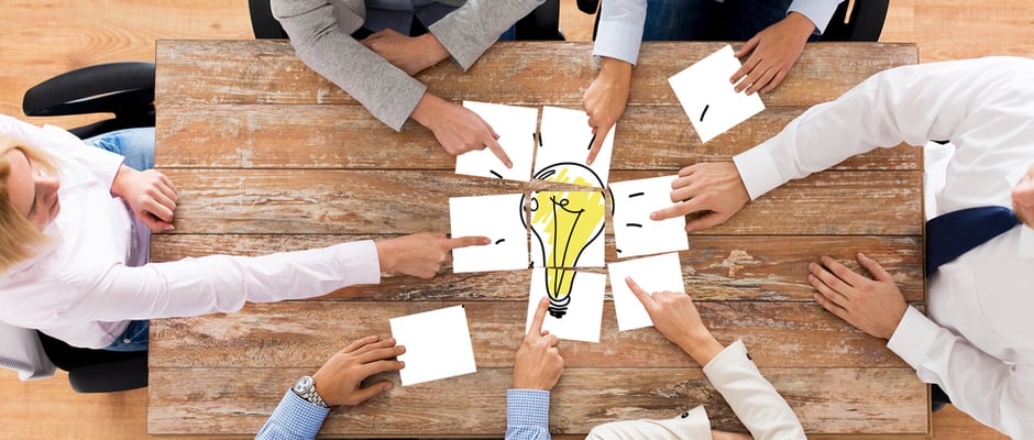 image of hands putting together a puzzle picture of a light bulb