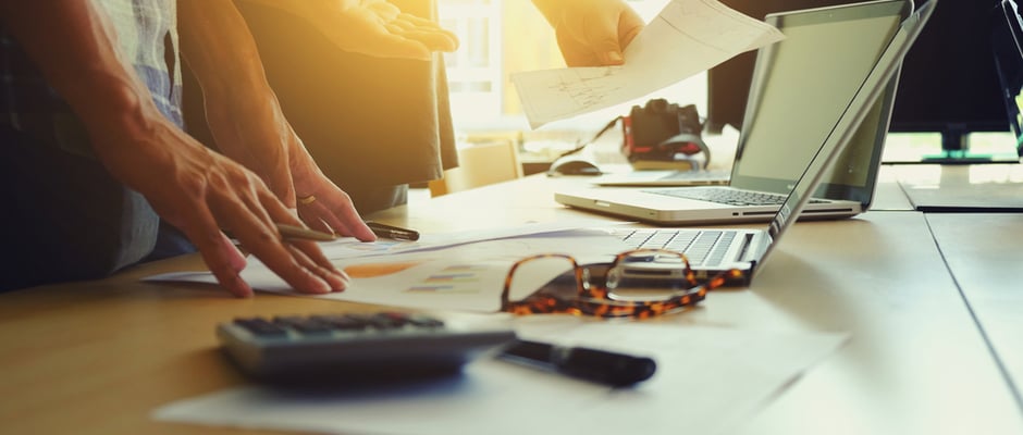 image of business people working over a desk covered with paperwork