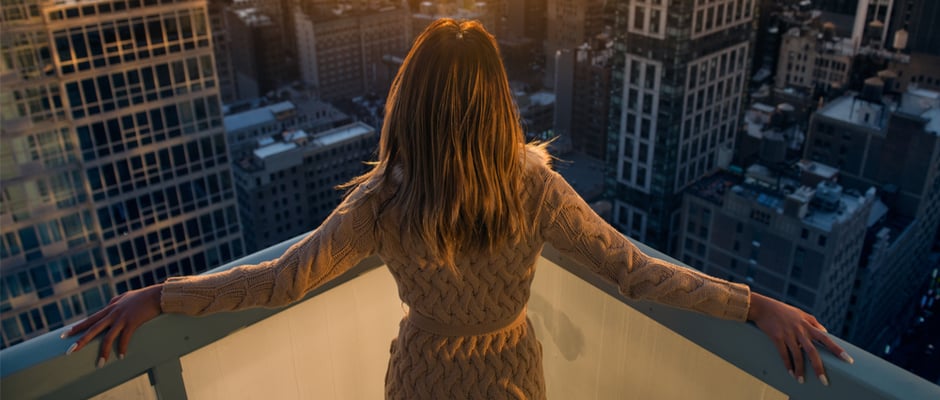 alt text image of business woman standing on balcony looking out across a city