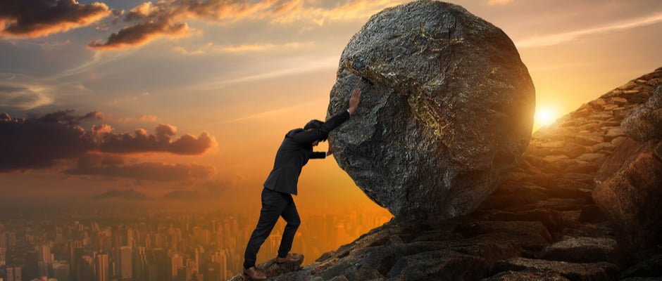 image of man pushing a large rock up a hill