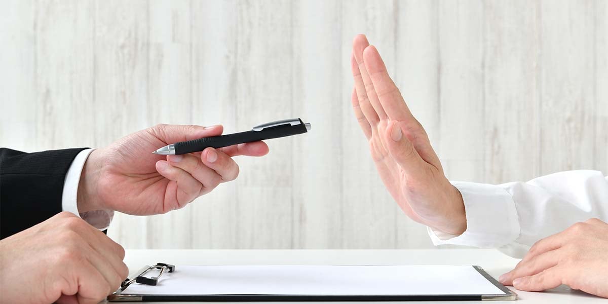 man's hand rejecting a pen to sign a contract