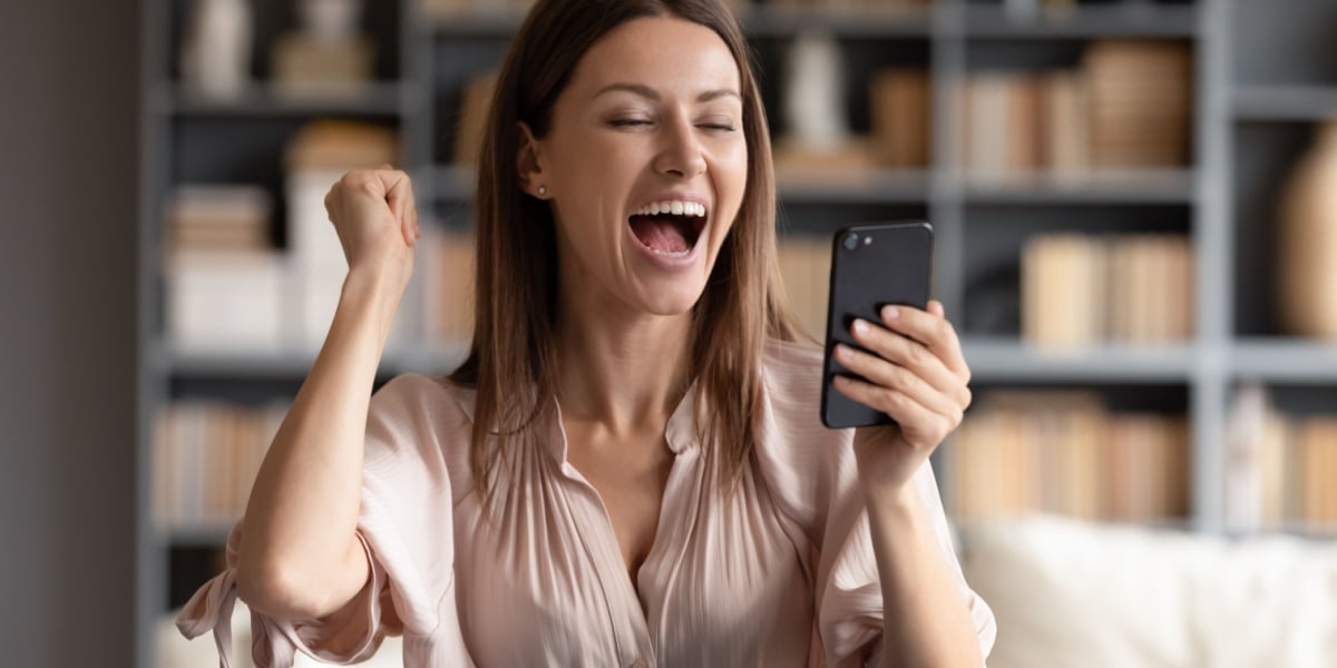 Woman pumping fist in excitement looking at phone