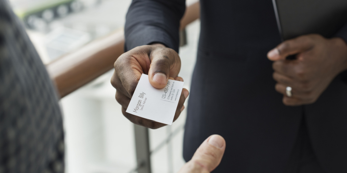 well dressed salesman hands business card to client