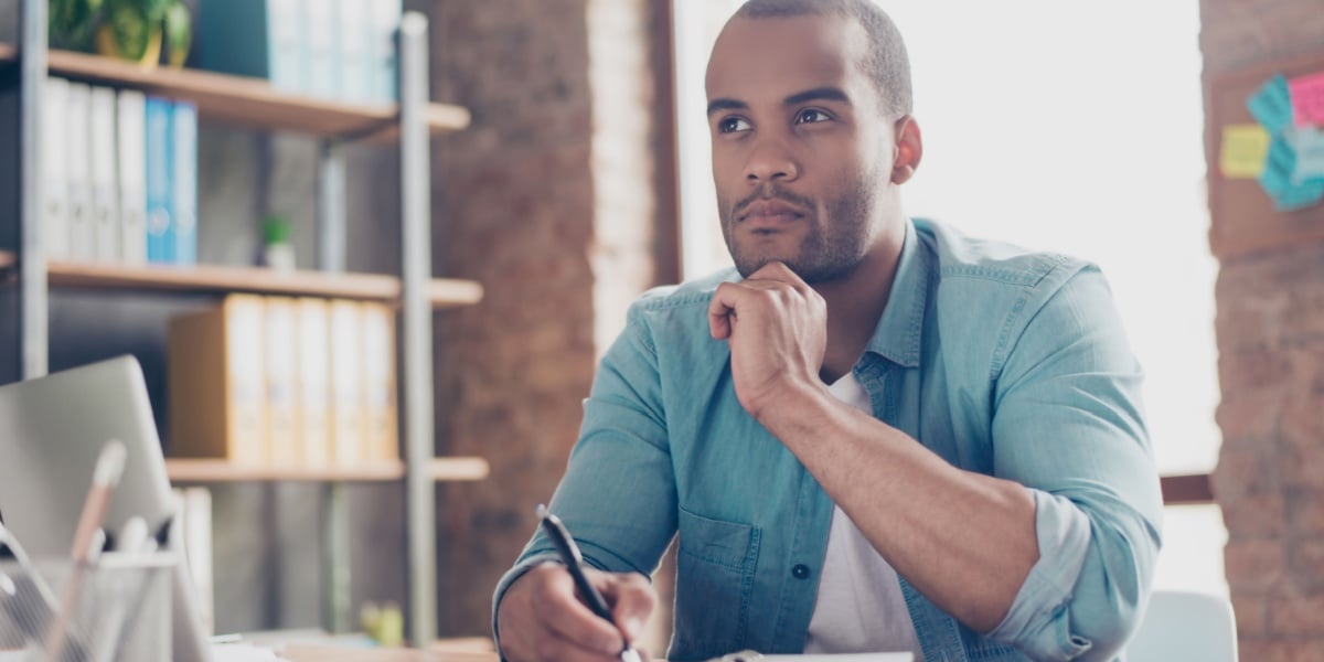 Man ponders with pen in hand