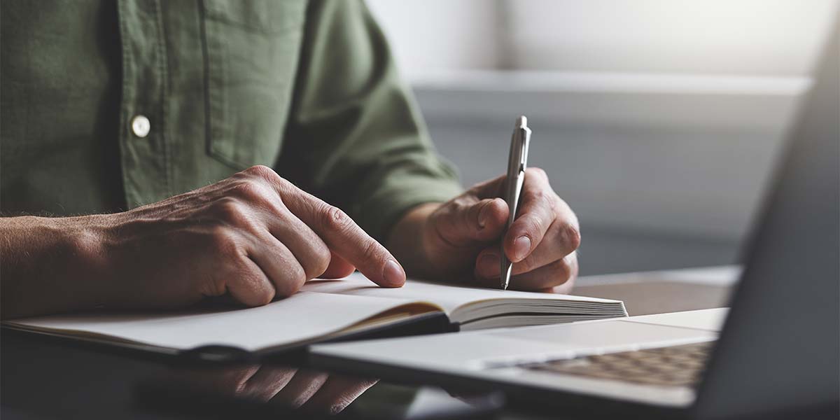 man writing his sales goals in a planner