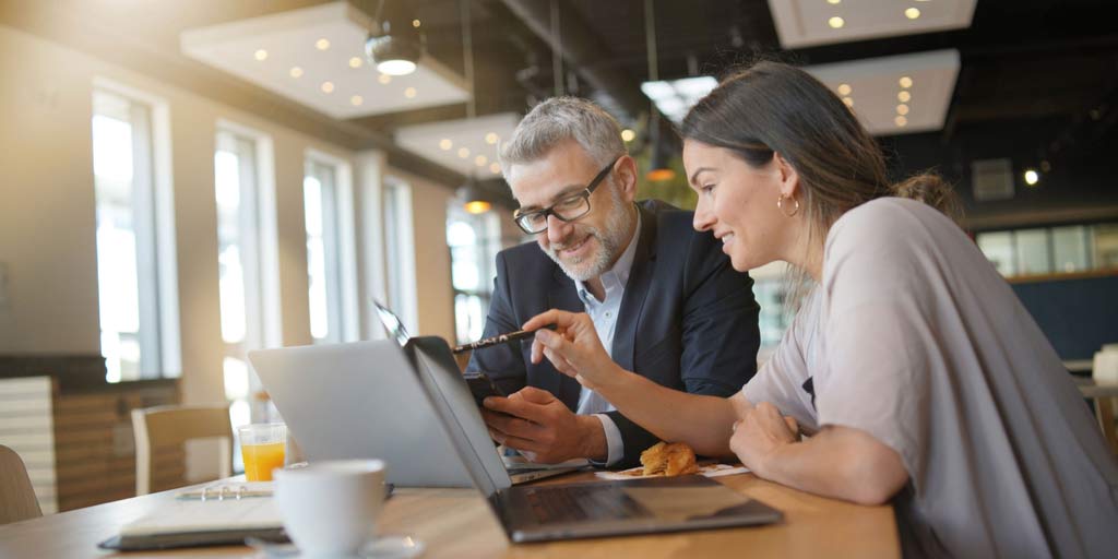 Man and woman look at computer during sales meeting