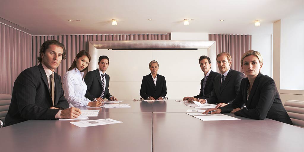 Bored group of executives in a conference room all looking at you