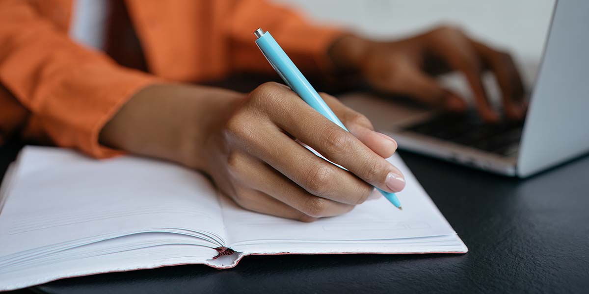 African American woman's hand writing in a notebook