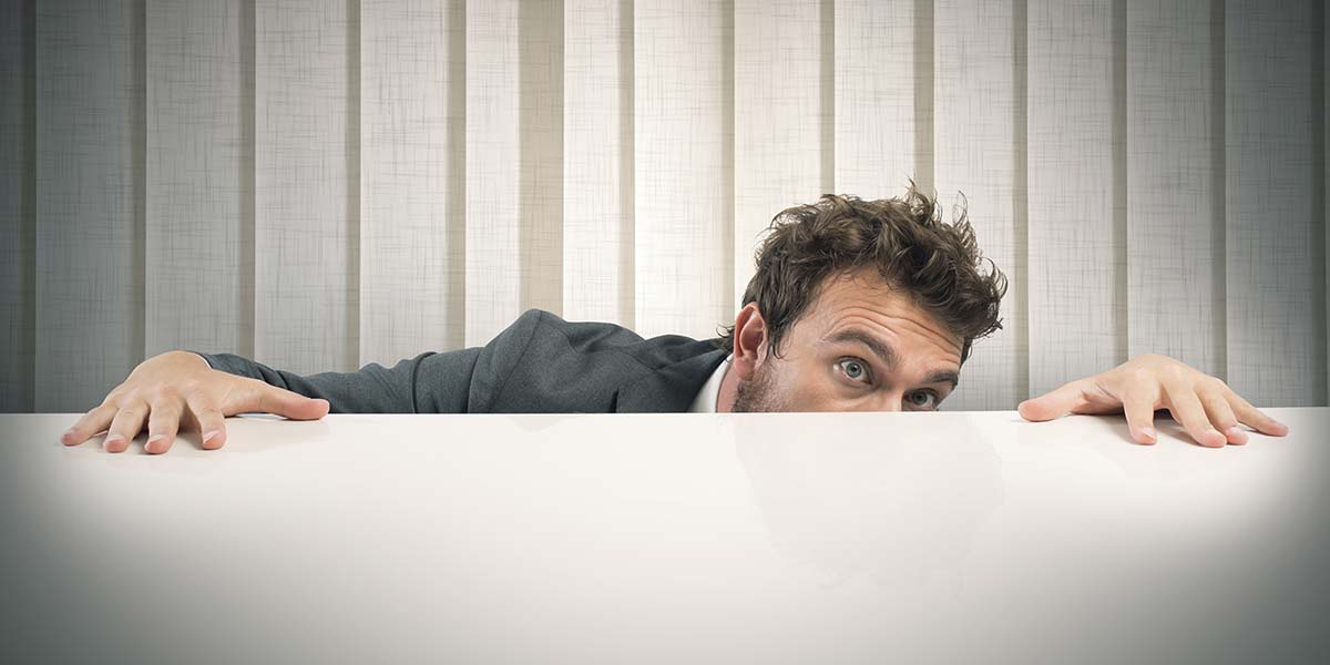 business man hiding behind his desk