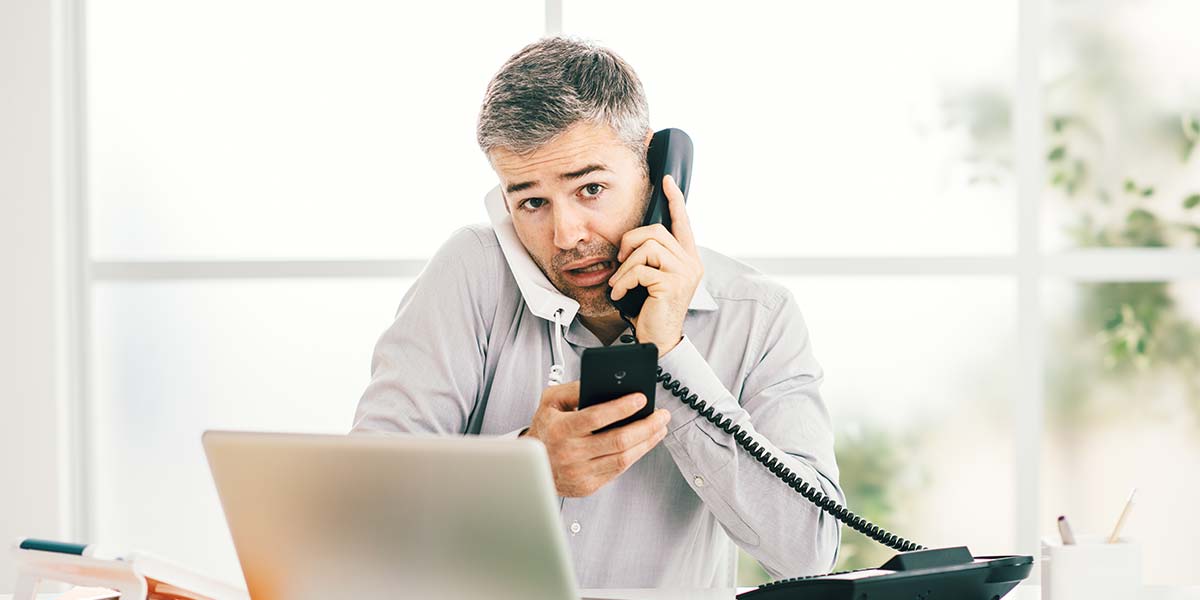 Stressed salesman holding multiple phones at once