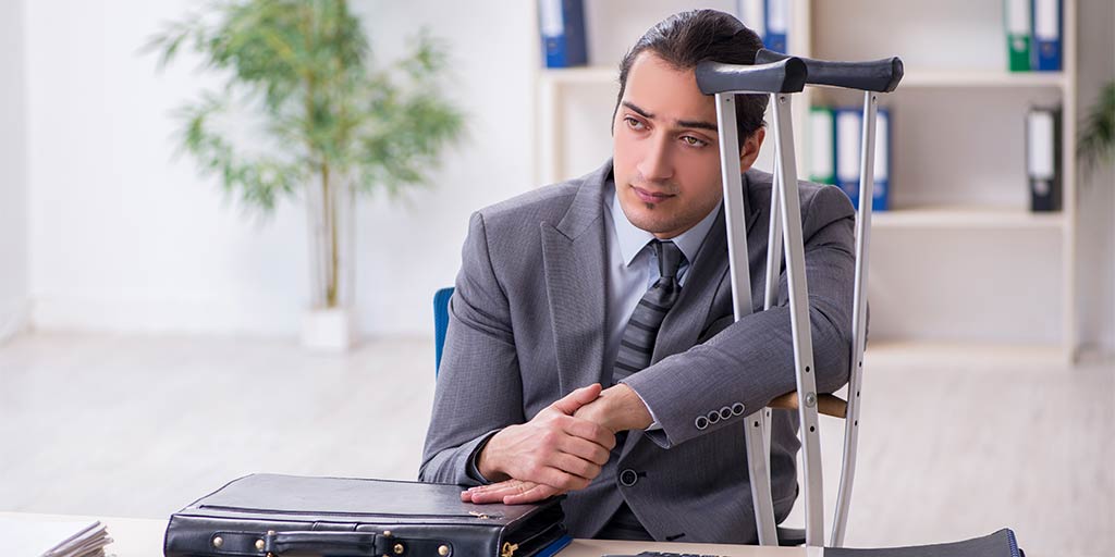 sad businessman holding onto crutches