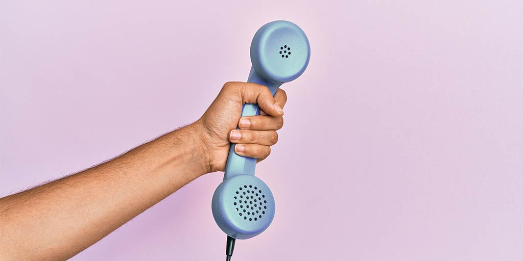 hand holding up telephone against backgrop