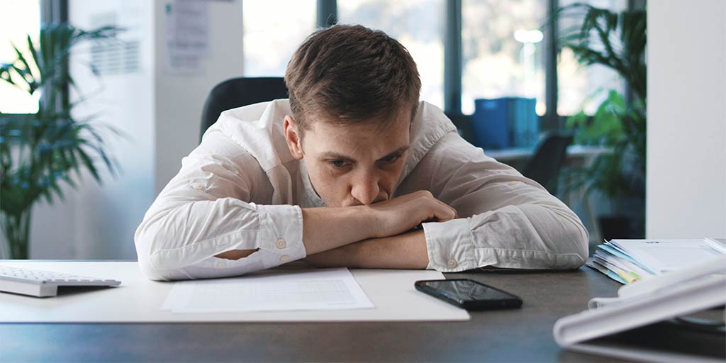 lazy salesman staring at his phone on the desk