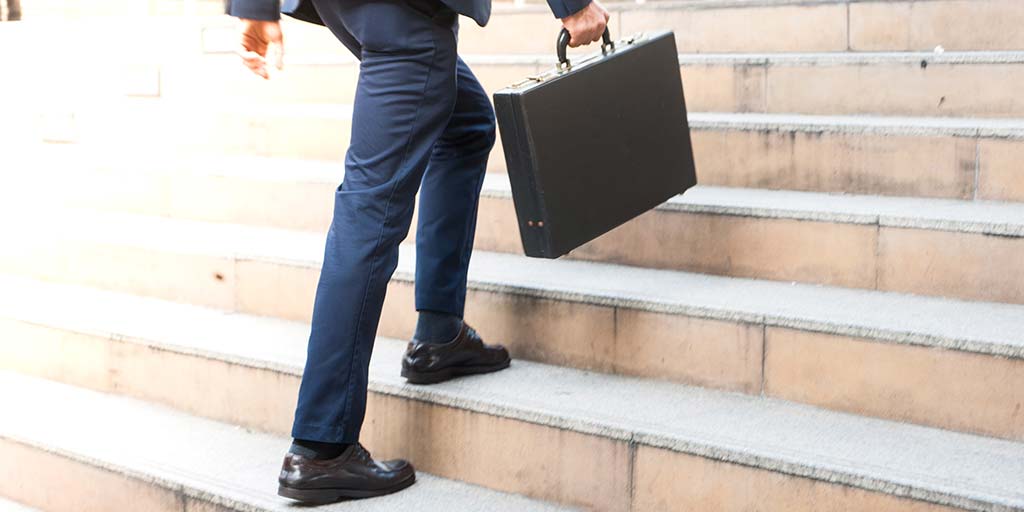 businessman holding briefcase walking up stairs