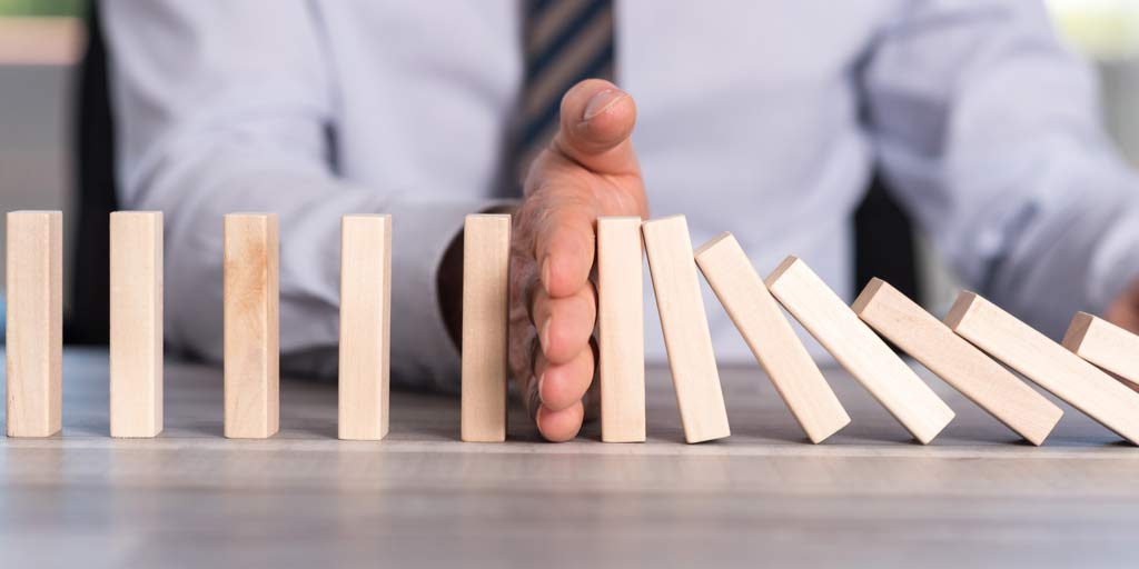 hand stopping dominos from falling
