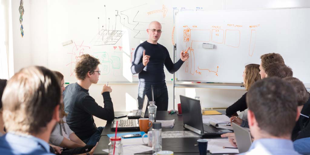 Man leading a business meeting at whiteboard